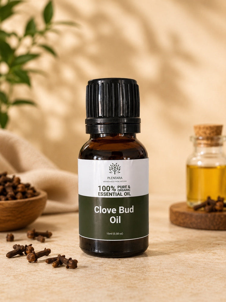 Clove bud essential oil in a glass bottle surrounded by dried cloves on a wooden surface